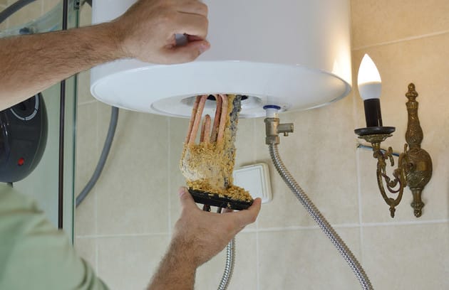 Technician removing mineral buildup from a water heater in Lansdale