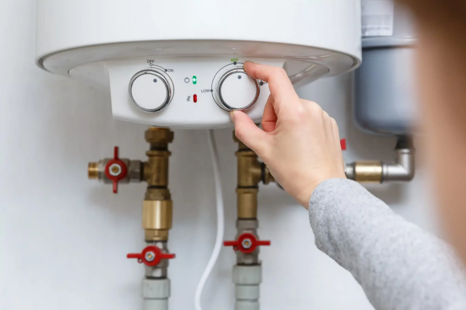 Homeowner adjusting the temperature controls on a water heater in Lansdale